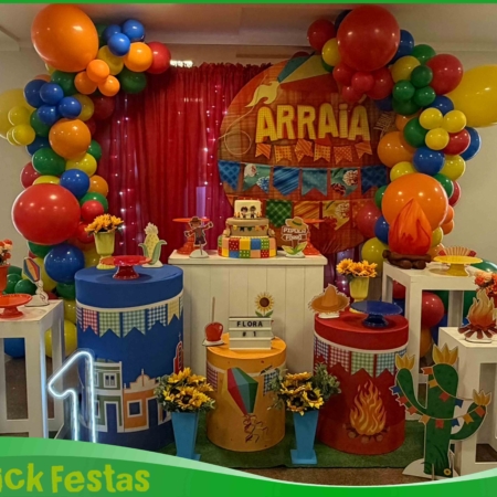 Decoração infantil Festa Junina montada em salão de festas com painel temático, bandeirinhas coloridas, balões, fogueira cenográfica, cactos decorativos, mesa personalizada e elementos caipiras para aniversário infantil na Freguesia do Ó, São Paulo.