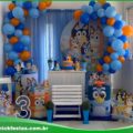 Decoração de festa infantil com tema Bluey, incluindo painel colorido, mesas decoradas e personagens da série.