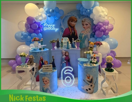 Decoração infantil Frozen com painel temático, balões em tons de azul e branco, mesa decorada e personagens Elsa e Anna para festa infantil na Freguesia do Ó SP.