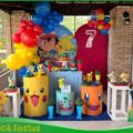 Decoração infantil tema Pokémon para locação, com painel temático, personagens Pokémon, mesa decorativa e elementos coloridos para festa de aniversário.